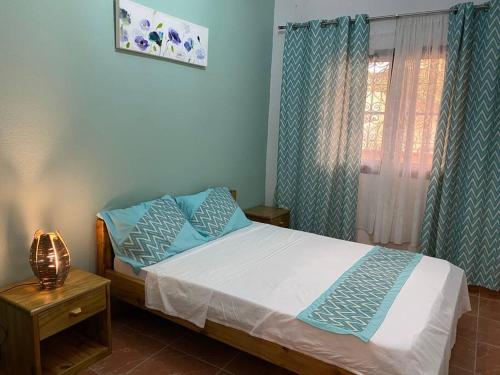 Un dormitorio con una cama con almohadas azules y una ventana en Tropical House en Pamandzi