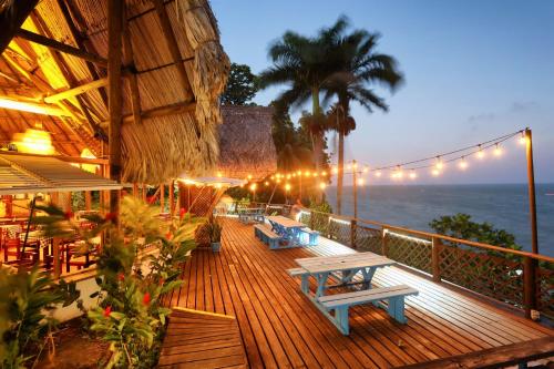 a deck with tables and benches on the beach at night at Villa Caribe in Lívingston