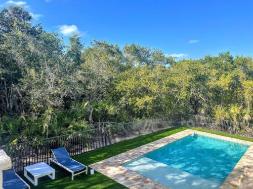 a swimming pool with two blue chairs next to a yard at Nature View #2 in Fort Myers Beach