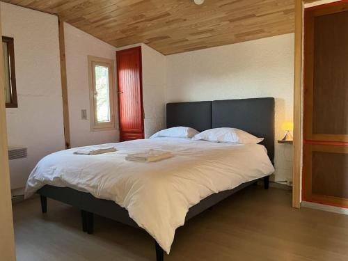 een slaapkamer met een groot bed met witte lakens bij Chalet hérisson in La-Roche-en-Ardenne