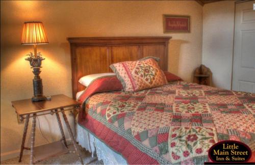 a bedroom with a bed with a quilt and a lamp at Little Main Street Inn in Banner Elk