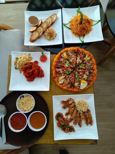 una mesa con varios platos de comida y una pizza en Fenet Hawassa Hotel, en Āwasa