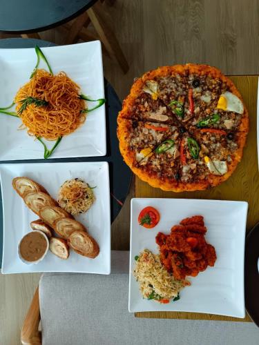 una mesa con tres platos de comida y una pizza en Fenet Hawassa Hotel, en Āwasa