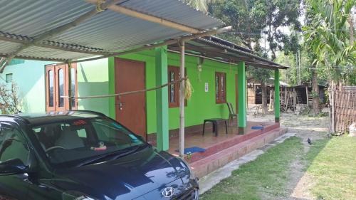 ein grünes Haus mit einem davor geparkt in der Unterkunft MANAS RAY HOMESTAY in Jyoti Gaon