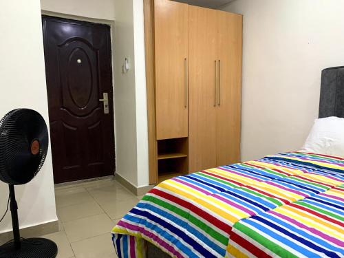 a bedroom with a colorful bed and a closet at Comfortable 2BDR Apt - Superb power supply, Wi-Fi, Kitchen, Netflix, Mins to Airport in Agege