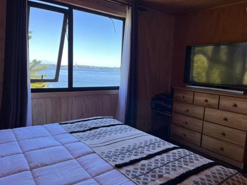 1 dormitorio con 1 cama, TV y ventana en Departamento con vista al Mar, en Ancud