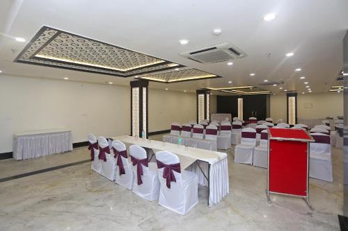 a banquet hall with white tables and red and white chairs at Collection O Pearl Blue in Tājganj