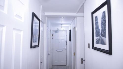 a hallway with white walls and pictures on the walls at Stunning 2-Bed Apartment in London in London