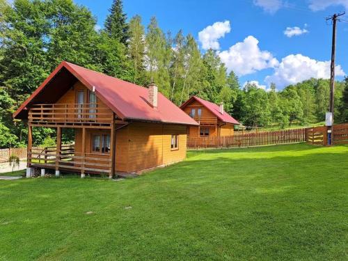une cabane en rondins avec un toit rouge sur un champ vert dans l'établissement Hiša na Planini, 