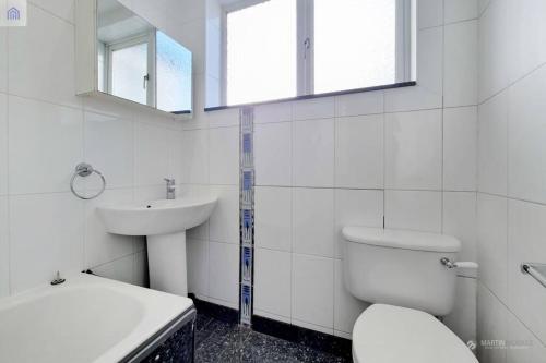 La salle de bains blanche est pourvue de toilettes et d'un lavabo. dans l'établissement Hertford Road Edmonton, à Ponders End