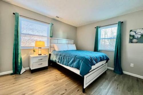 1 dormitorio con 1 cama con edredón azul y 2 ventanas en Newly Remodeled Apt Middletown, Ohio FREE Laundry, en Middletown