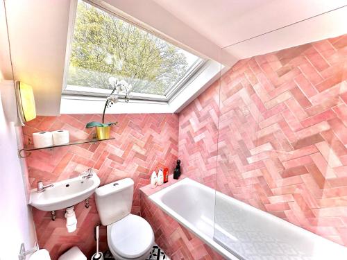 Enticing 2 Bed 2 Bath Flat in Hackney with garden في لندن: حمام مع مرحاض ومغسلة وحوض استحمام
