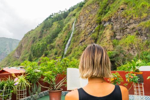 a woman standing on a balcony looking at a waterfall at Hotel De Mi Pueblo in Baños
