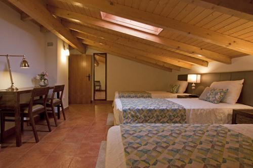 a bedroom with two beds and a table and a desk at Herdade da Urgueira in Vale de Pousadas
