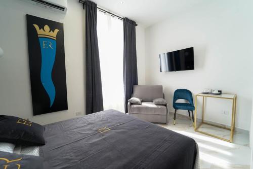 Schlafzimmer mit einem Bett, einem TV und einem Stuhl in der Unterkunft Élite Rooms in Neapel