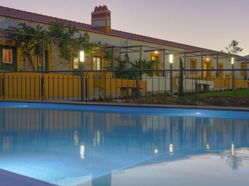 a building with a swimming pool in front of a building at Herdade da Urgueira in Vale de Pousadas