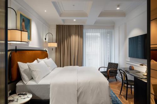 um quarto de hotel com uma cama branca e uma secretária em AS Boutique Hotel, superior em Ljubljana
