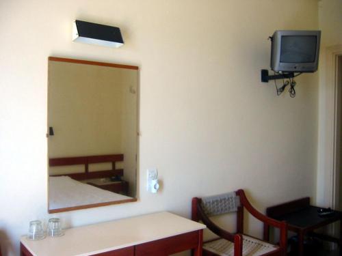 a room with a mirror and a table and a tv at Hotel Avra in Egina