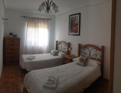 een slaapkamer met twee bedden, een ladekast en een raam bij La tranquila Manchuela in Alborea