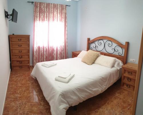 een slaapkamer met een bed met witte lakens en een raam bij La tranquila Manchuela in Alborea