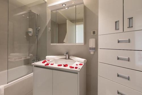 un baño con lavabo con rosas rojas. en Bw Apartments Lux - Belgrade Waterfront, en Sajmište