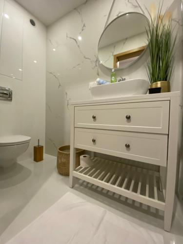een witte badkamer met een wastafel en een spiegel bij Rozmarynowy in Opole