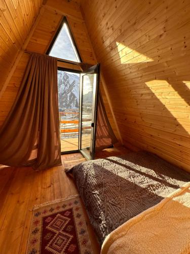 sypialnia z łóżkiem i oknem w kabinie w obiekcie AURA Cottages w mieście Stepancminda