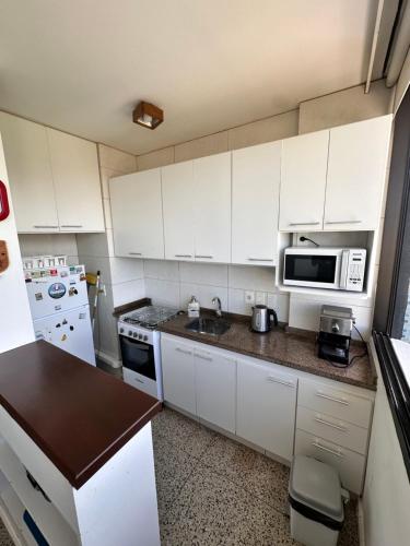 Apartamento en Edificio Uruguay (Punta del Este) في بونتا دل إستي: مطبخ بدولاب بيضاء ومغسلة وميكروويف