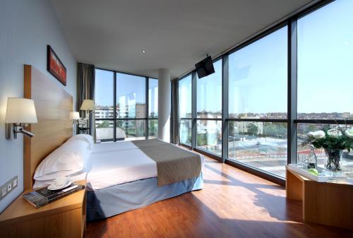 a hotel room with a bed and large windows at Exe Sevilla Palmera in Seville
