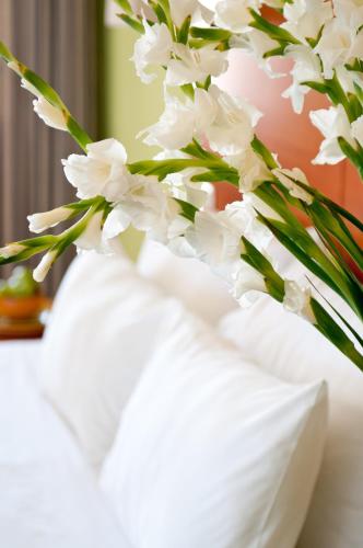 a white vase with white flowers in it at Prima Music Hotel in Eilat