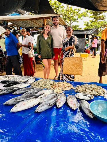 a group of people standing in front of a table of fish at Villa Aroshina with cooking class in Galle