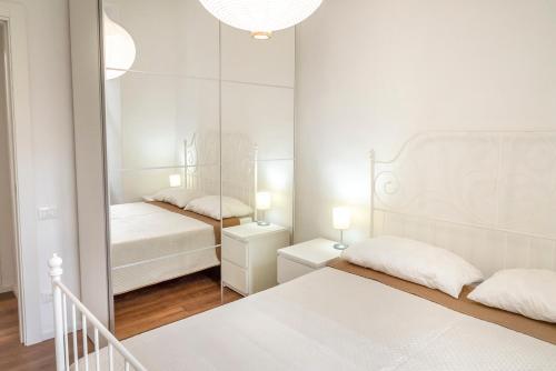 a white bedroom with two beds and a mirror at O01 - Osimo, trilocale ristrutturato in centro storico in Osimo