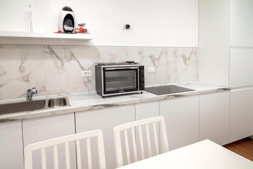 a white kitchen with a microwave on a counter at O01 - Osimo, trilocale ristrutturato in centro storico in Osimo