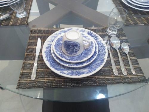 einen Tisch mit einer blauen und weißen Tasse und Platten darauf in der Unterkunft #Apto a beira-mar na Praia do Sul de Ilhéus in Ilhéus