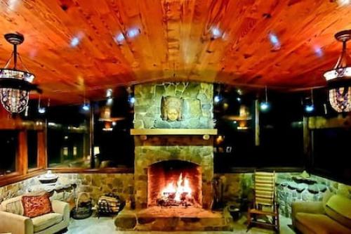 a living room with a stone fireplace and a couch at Treehouse at Castle in Stanardsville