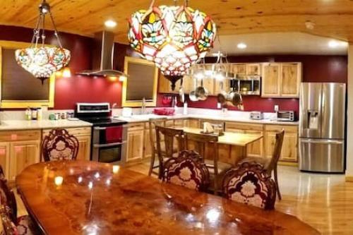 a kitchen with a wooden table with chairs and a kitchen with a refrigerator at Treehouse at Castle in Stanardsville