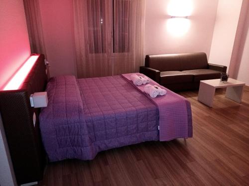 a small bedroom with a pink bed and a couch at Locanda LaRotonda in Villa Verucchio