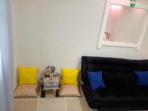 a living room with a black couch and yellow pillows at Spring house in Qaryat Shākūsh
