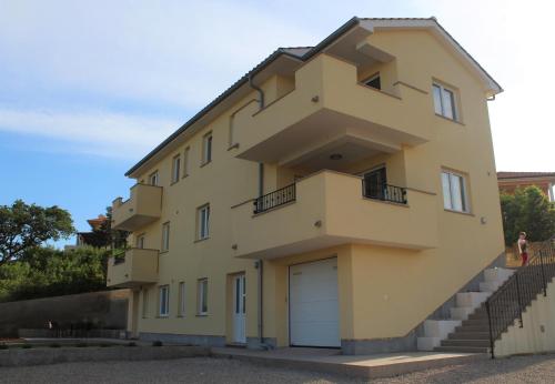 a large yellow building with a garage at Apartmani Marin1 in Vrbnik