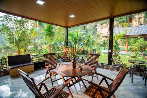 a dining room with a table and chairs and a large window at Hoang Minh Mountainside Villa in Ninh Binh