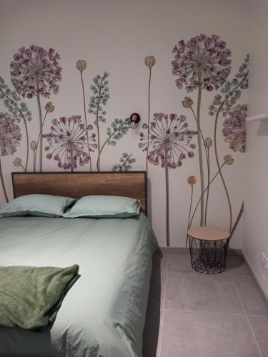 a bedroom with a bed with purple flowers on the wall at La cour fleurie, tout confort in Dijon