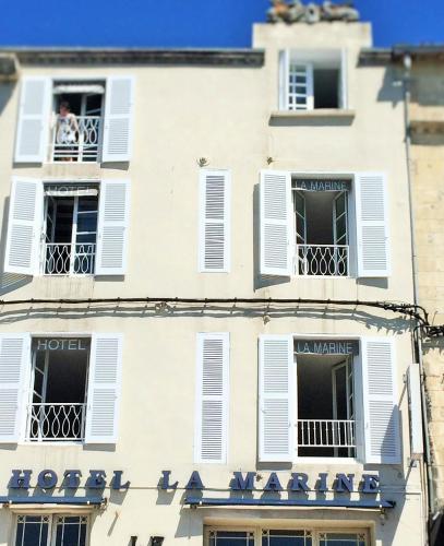 a man looks out from a balcony of a building at Hotel La Marine, Vieux Port in La Rochelle