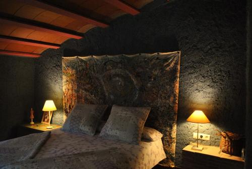 a bedroom with a large bed with two lamps at Masia El Riscle - Moli Del Pont in Cornudella