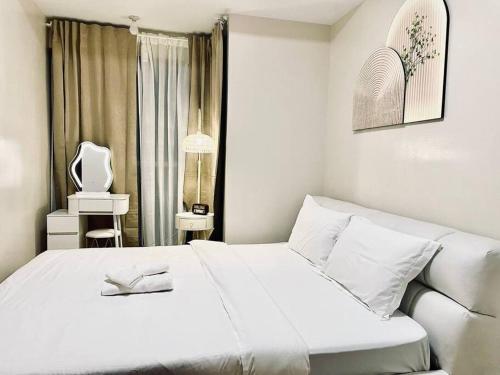 a white bedroom with a white bed and a window at Thompson Suites - 2-beds near OKADA, Bayshore 2 in Manila