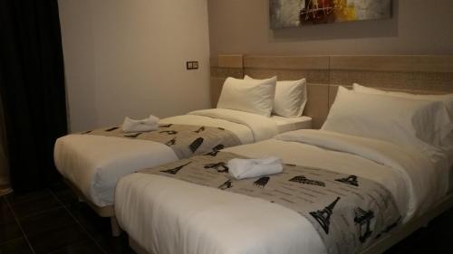 two beds in a hotel room with white sheets at Hotel A44 in Tetouan
