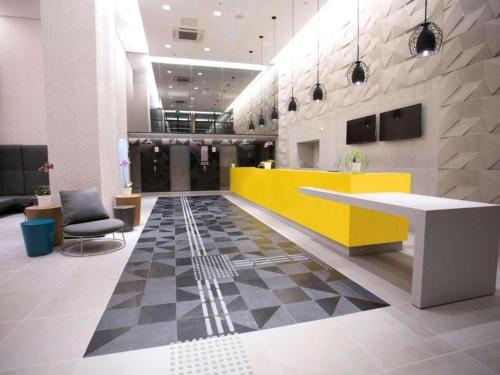 a lobby with a yellow counter and a checkered floor at Suíte Apart Hotel Mondial Salvador in Salvador