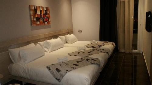 two beds in a hotel room with white sheets and pillows at Hotel A44 in Tetouan