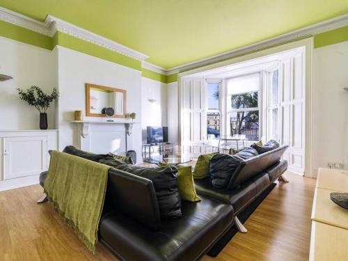 a living room with a black leather couch and a table at Longsands Beach Apartment 1 Tynemouth Free Onsite Parking in Tynemouth