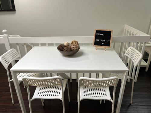 a white table with chairs and a bowl of fruit on it at Bright, Private, Peaceful Suite with Retail Conveniences Steps Away in Toronto