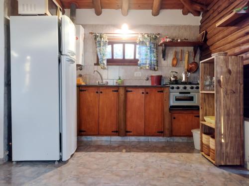 eine Küche mit Holzschränken und einem weißen Kühlschrank in der Unterkunft Cabaña de troncos en Nono, Córdoba in Nono